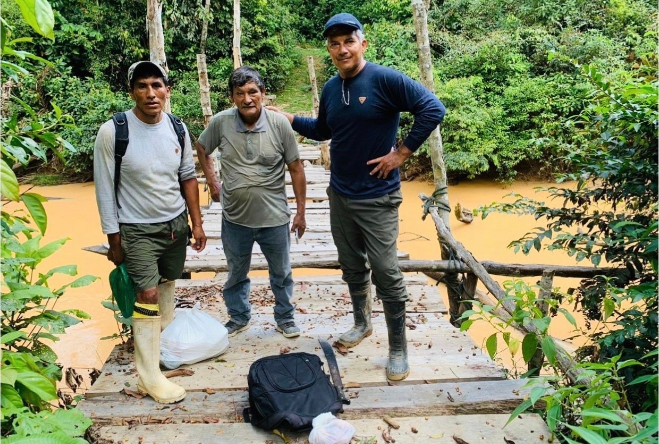 ORO field team with community members on a jungle bridge — going where communities are